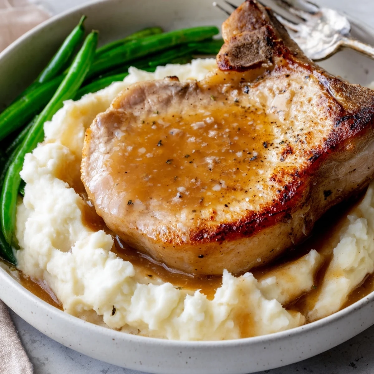 Juicy pork chops nestled on creamy cheddar mash, topped with savory gravy.
