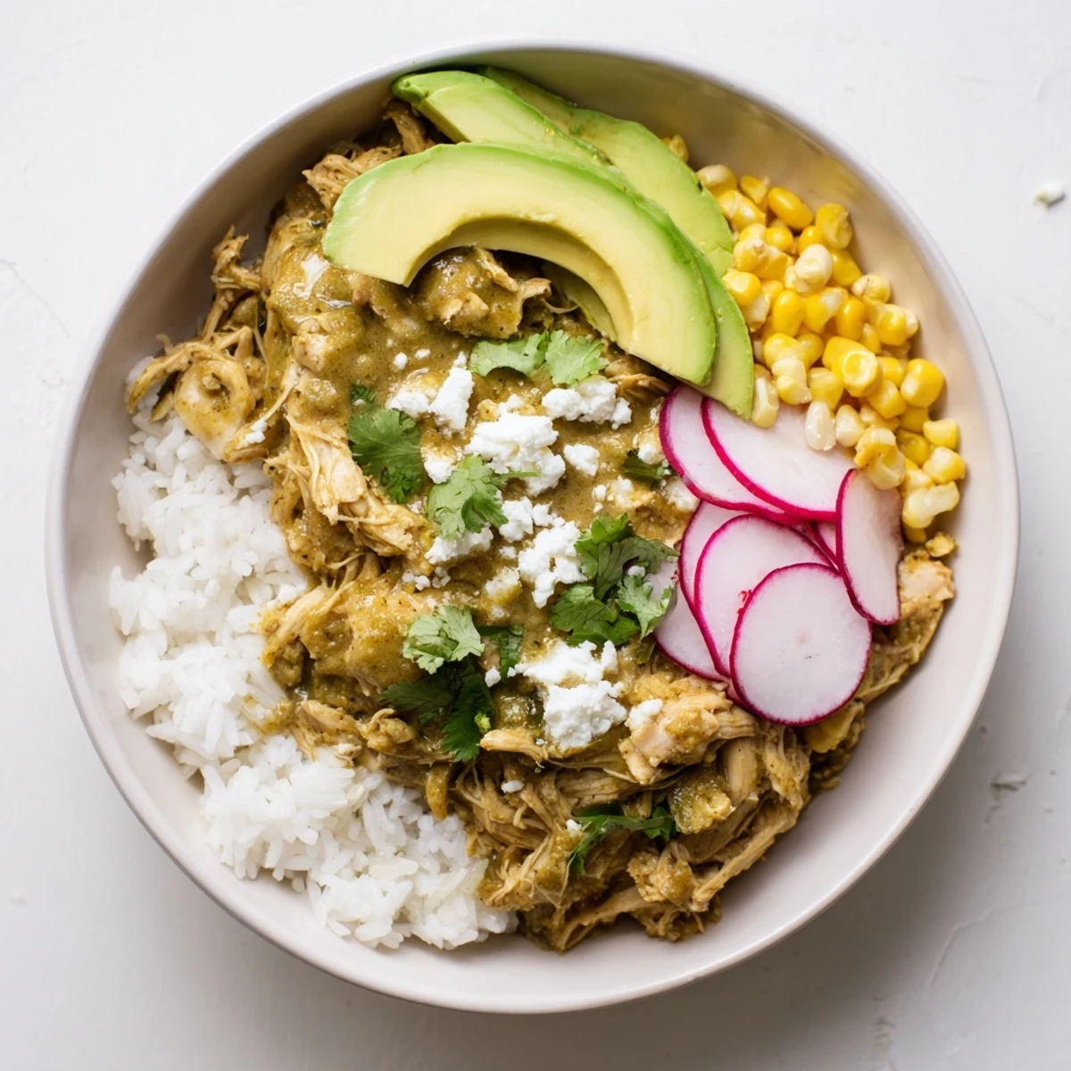 Green Enchiladas Rice Bowl overflowing with chicken, black beans, and vibrant green sauce, ready to serve.