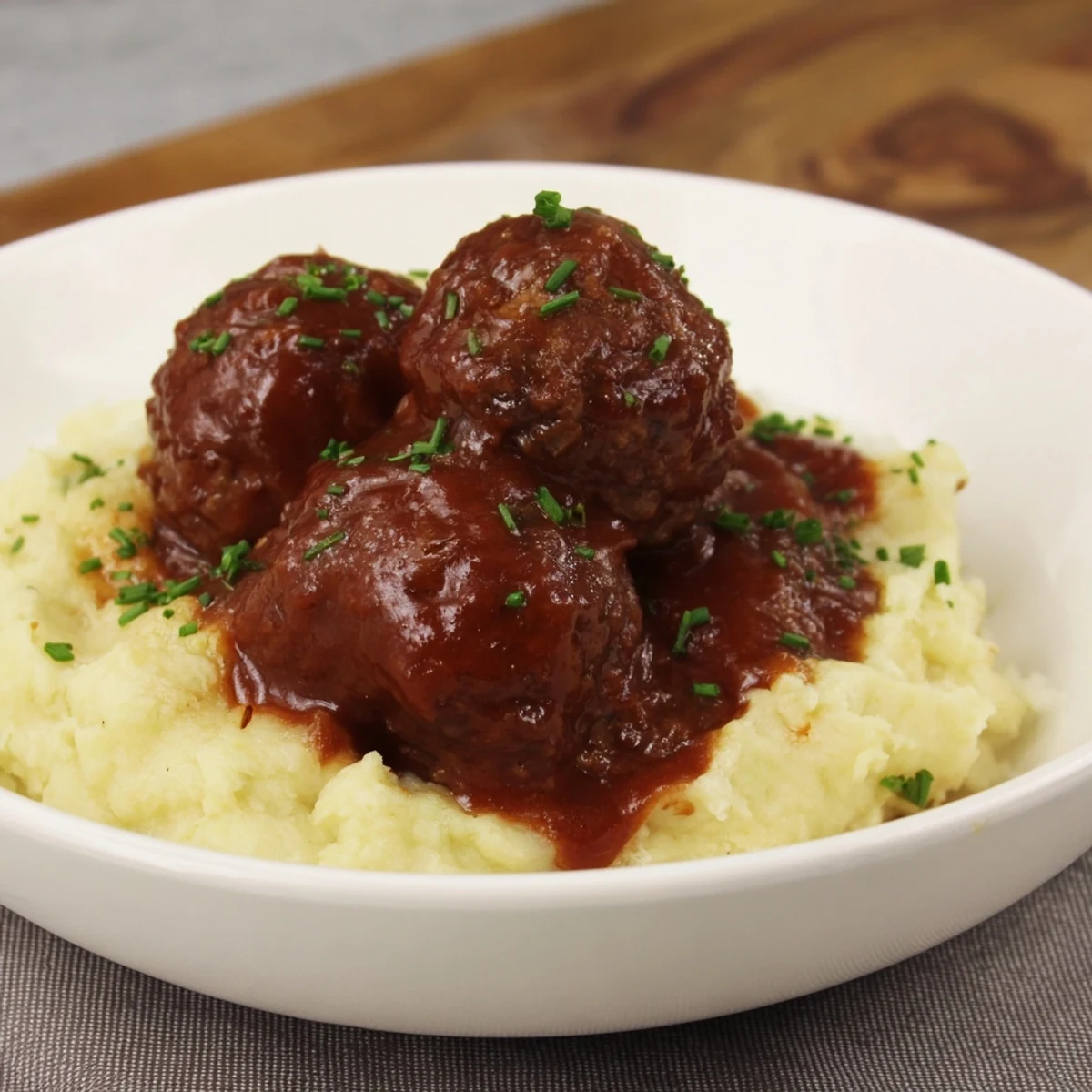 A close-up view of BBQ Meatballs & Mashed Potatoes, the glazed meatballs glistening with flavorful BBQ sauce.