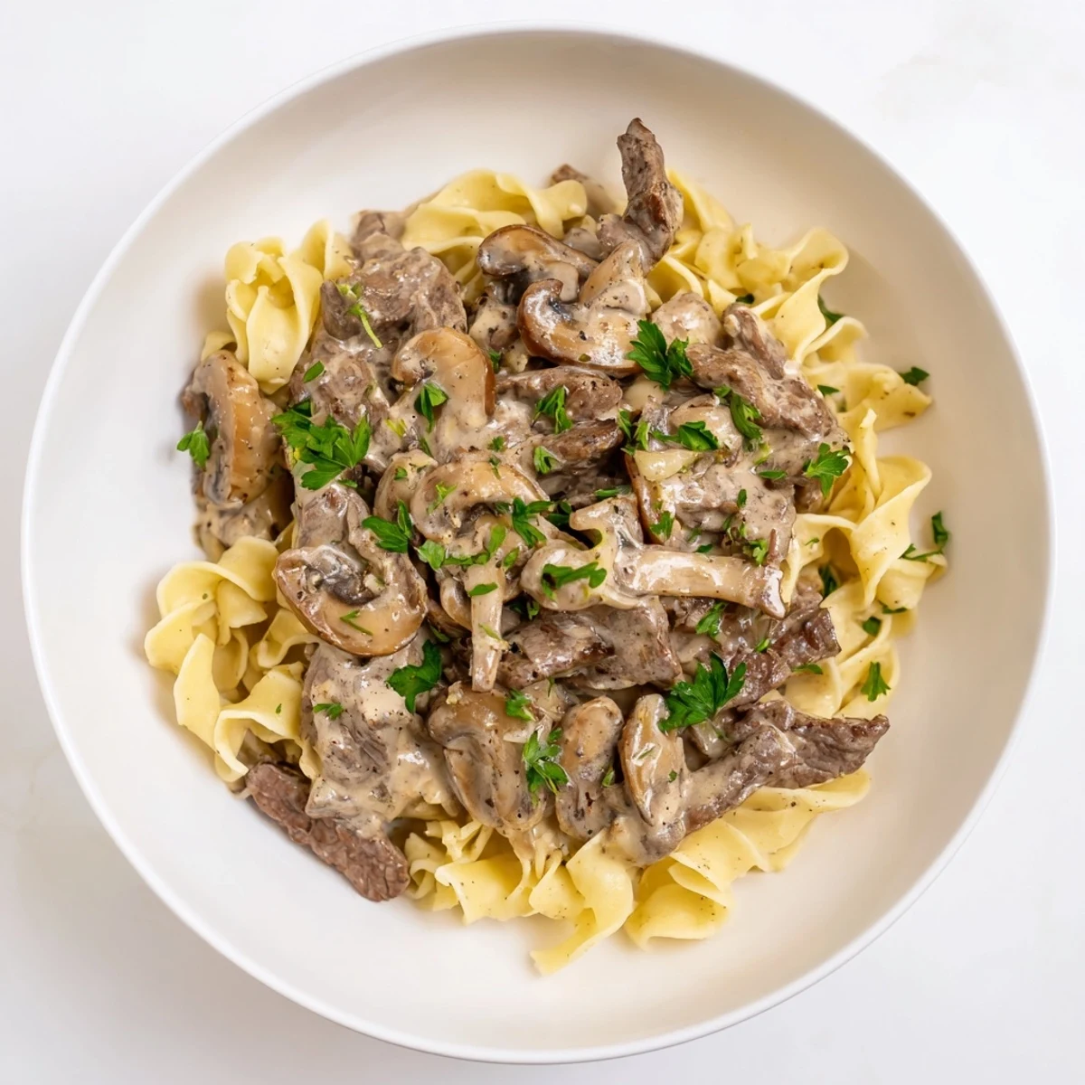 Creamy Mushroom Beef Stroganoff: A comforting bowl of tender beef and creamy mushroom sauce atop egg noodles.