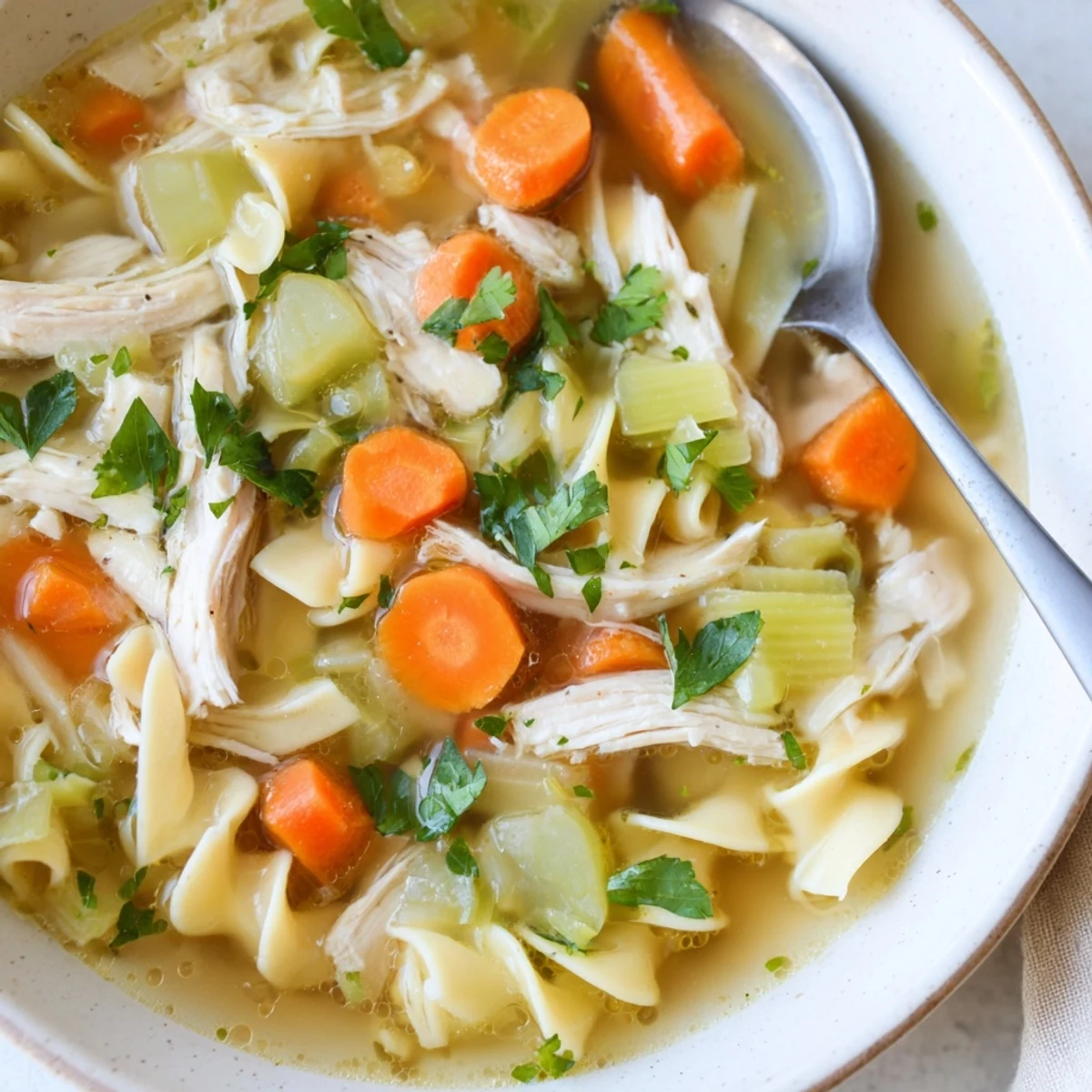 Hearty homemade chicken noodle soup, with golden egg noodles and fresh parsley, ready to enjoy.