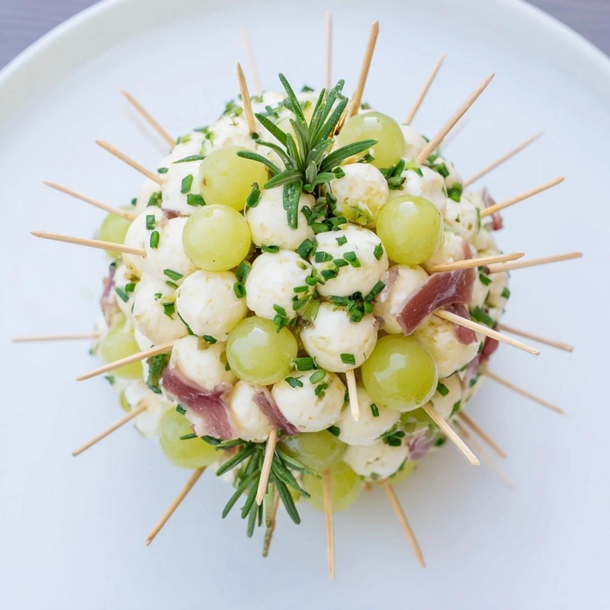 Close up view of the festive Mistletoe Kissing Ball, showcasing fresh herbs and colorful prosciutto ribbons.