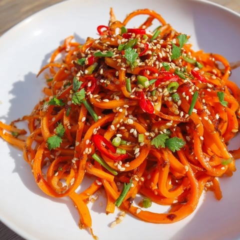 Vibrantly-colored Carrot Ribbon Salad Asian-Style is bathed in a glossy dressing, ready to be enjoyed.