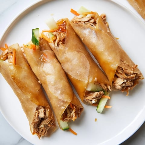 Golden, crispy Garlicky Pulled Chicken Wraps beautifully showcase tender chicken and fresh vegetables inside.