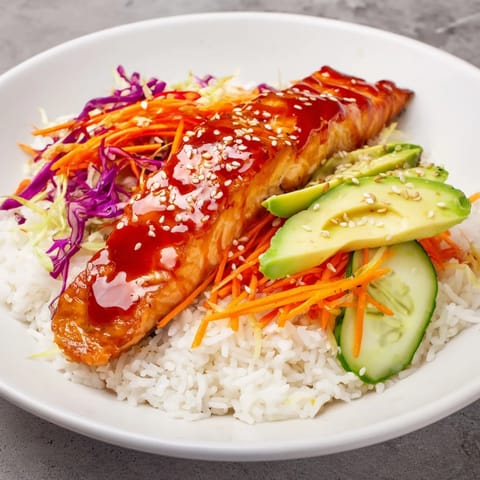 A delicious sweet chili salmon rice bowl, showcasing flaky salmon and colorful, vibrant toppings.