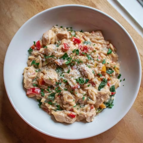 Imagine the vibrant red peppers in this One-Pot Cajun Chicken Alfredo Orzo recipe, served hot and delicious.