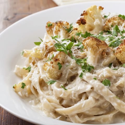 Roasted Cauliflower Alfredo sauce over pasta, featuring golden-brown roasted cauliflower florets blended with garlic and nutmeg.