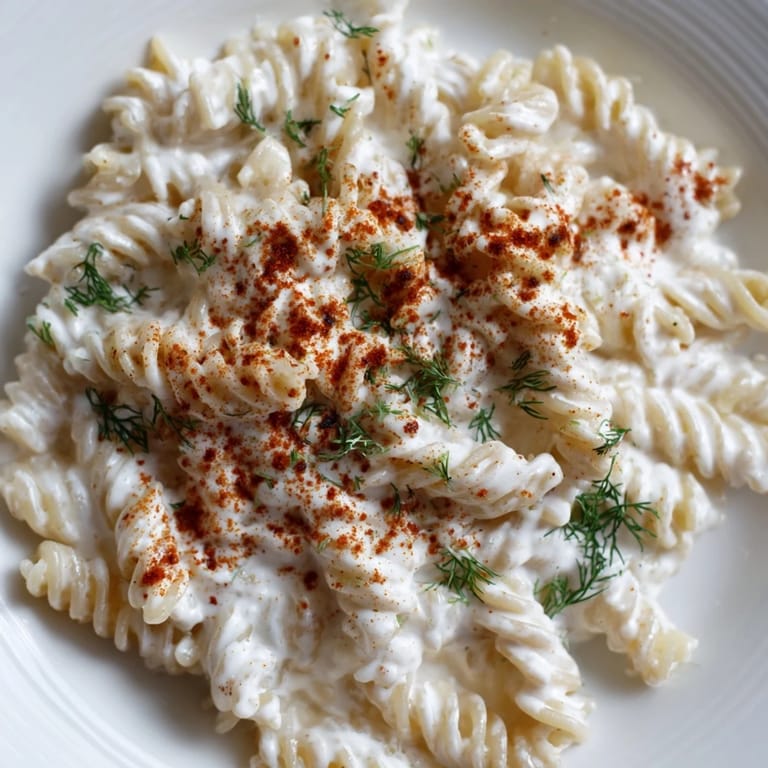 Warm Turkish Yogurt Pasta, topped with melted spiced butter and fresh herbs for a delicious meal.